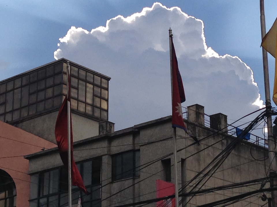 Bâtiment avec drapeaux népalais et nuages spectaculaires.