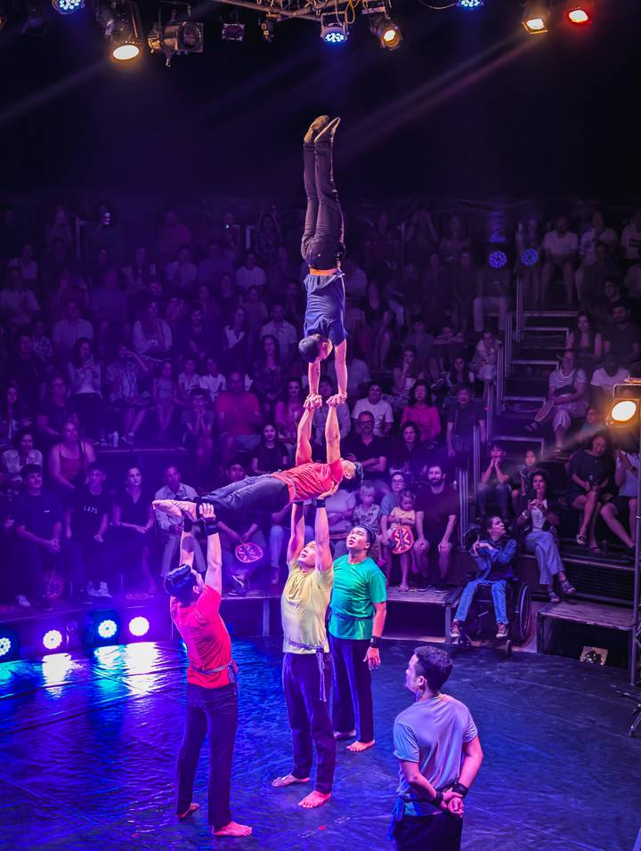 Actuación acrobática con múltiples personas equilibrándose unas sobre otras.