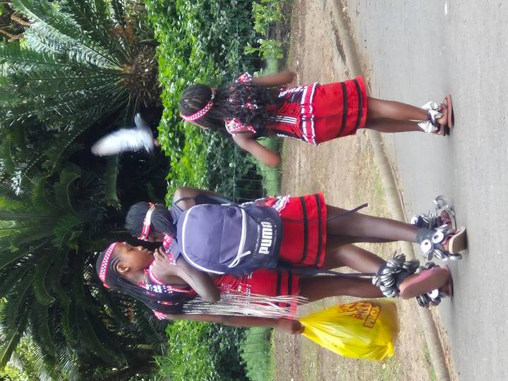 Un grupo de personas bailando con vegetación en un camino de tierra.