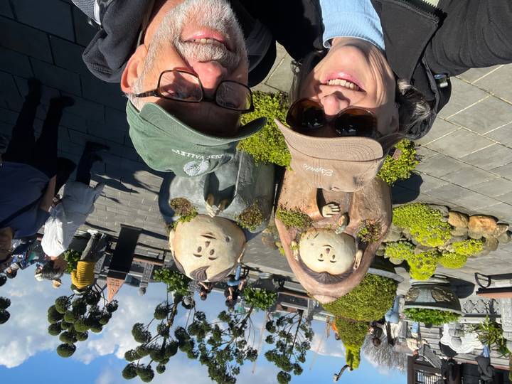 Pareja tomándose una selfie con esculturas de jardín caprichosas de fondo.