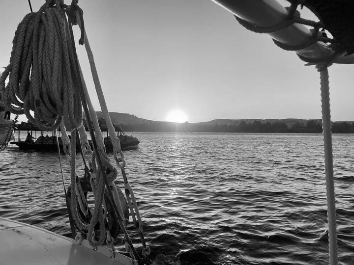 Une image en noir et blanc d'un coucher de soleil sur une rivière.