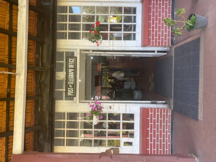 Entrée d'un bureau de poste et télégraphe vintage avec des personnes à l'intérieur.