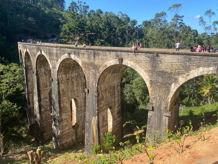 Pont historique à neuf arches avec des touristes qui marchent dessus.