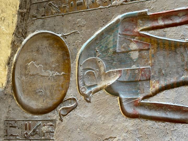 Relieve egipcio detallado que representa una deidad en una pared de piedra.