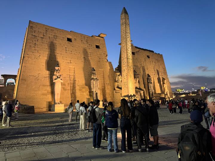 Fachada del templo con grandes estatuas iluminadas por la noche.