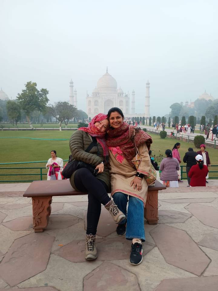Dos mujeres posando con el Taj Mahal de fondo.