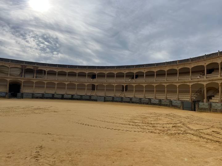 Une arène de corrida vide avec des motifs d'ombre sur le sable.