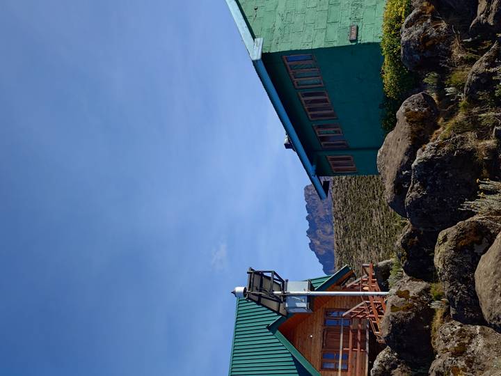 Bâtiments au pied d'une montagne avec un ciel bleu dégagé.