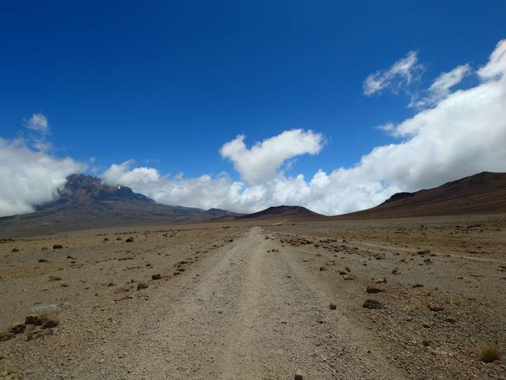 Sentier menant vers un sommet lointain avec un ciel dégagé.