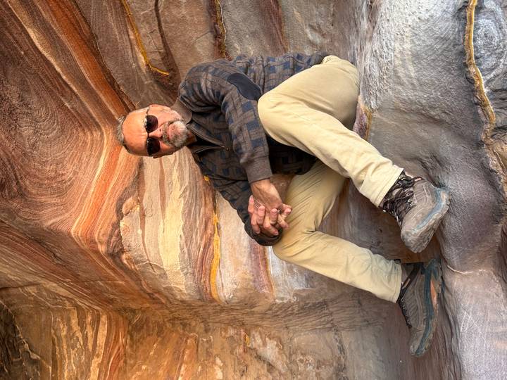 Personne assise à l'intérieur d'une grotte avec des formations rocheuses colorées.