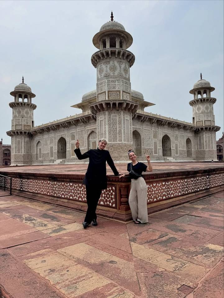 Dos personas paradas alegremente frente a un edificio arquitectónico histórico.