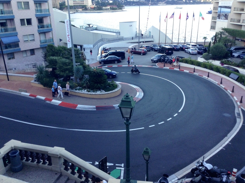 Rue courbe de la ville avec des voitures garées et un bâtiment en arrière-plan.