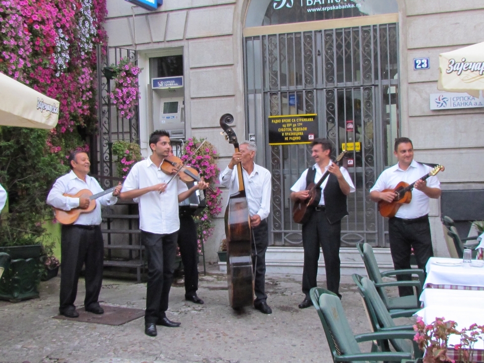 Musiciens de rue jouant des instruments près d'un café.