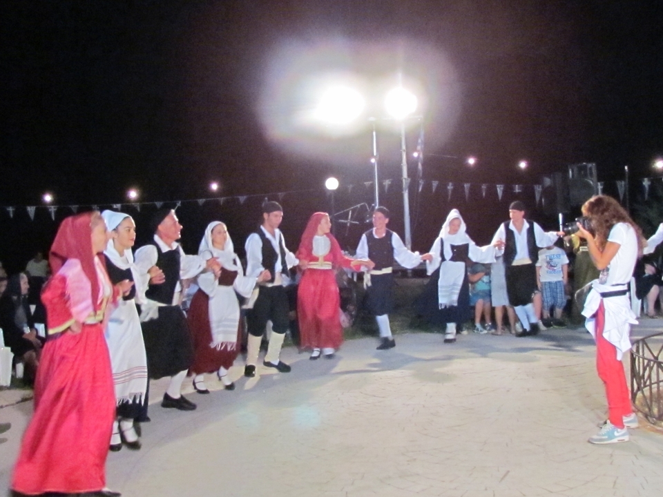 Groupe de personnes dansant en tenue traditionnelle sous des lumières vives.