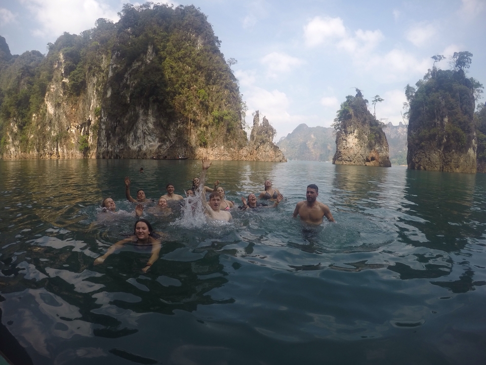 Group of people swimming in a lake surrounded by scenic cliffs.
