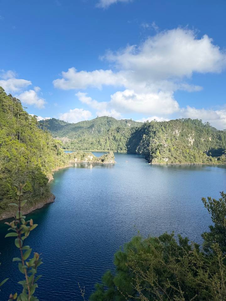 Serene lake view with green hills in the background under a bright sky.