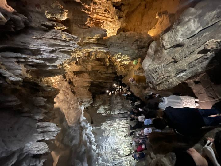 Höhle mit Stalaktiten und einer großen Gruppe von Besuchern im Inneren.