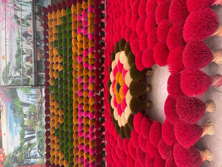 Bunte Räucherstäbchen in einem blumenähnlichen Muster angeordnet.