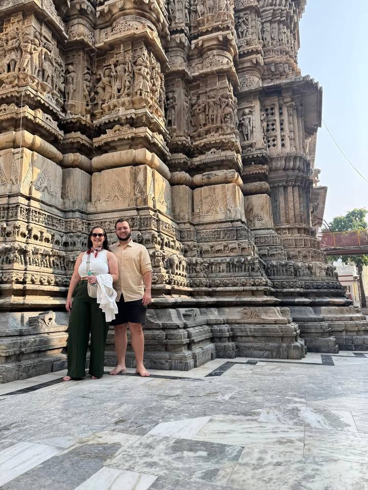 Una pareja posando frente a una estructura de piedra tallada.