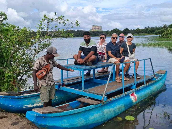 Un groupe de personnes sur un bateau avec la forteresse rocheuse de Sigiriya en arrière-plan.