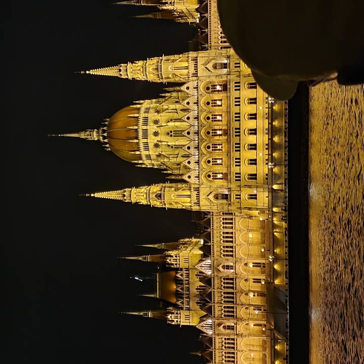 Bâtiment du Parlement illuminé la nuit, reflété dans la rivière.