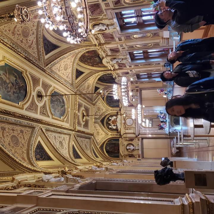 Intérieur d'une pièce richement décorée avec des personnes qui observent.