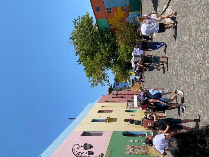 Rue animée de Caminito avec des touristes et des bâtiments colorés.