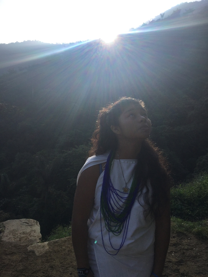 Young girl bathed in dramatic sun rays looking upward in a jungle valley.
