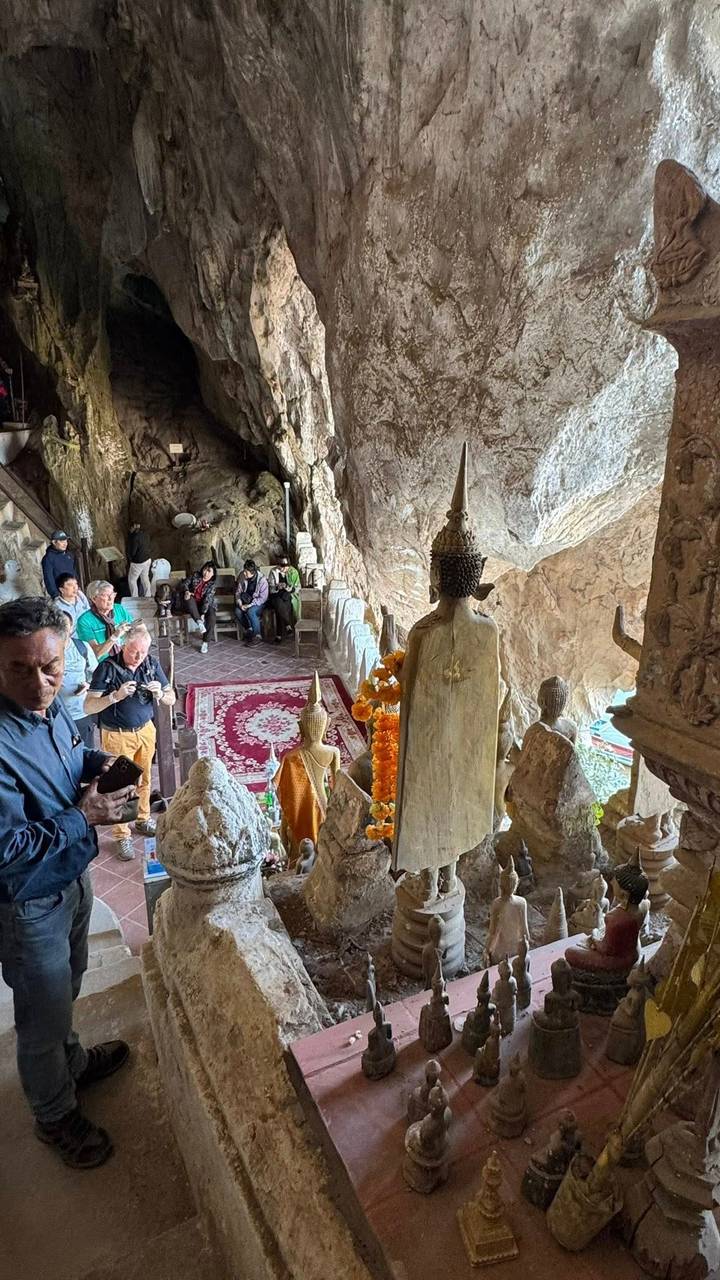 Turistas dentro de una cueva con estatuas budistas.
