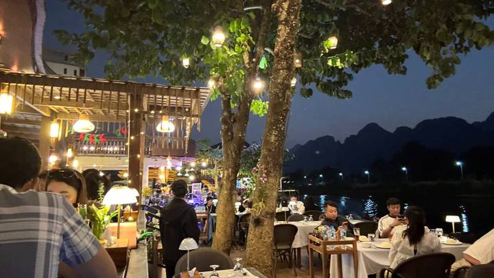 Gente cenando junto al río por la noche.