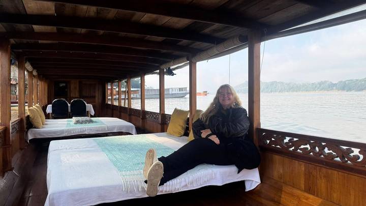 Mujer relajándose en un barco con vista al río.