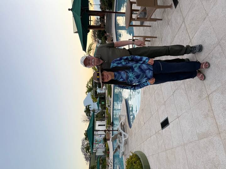 Couple posant près d'une piscine avec vue sur les montagnes au loin.