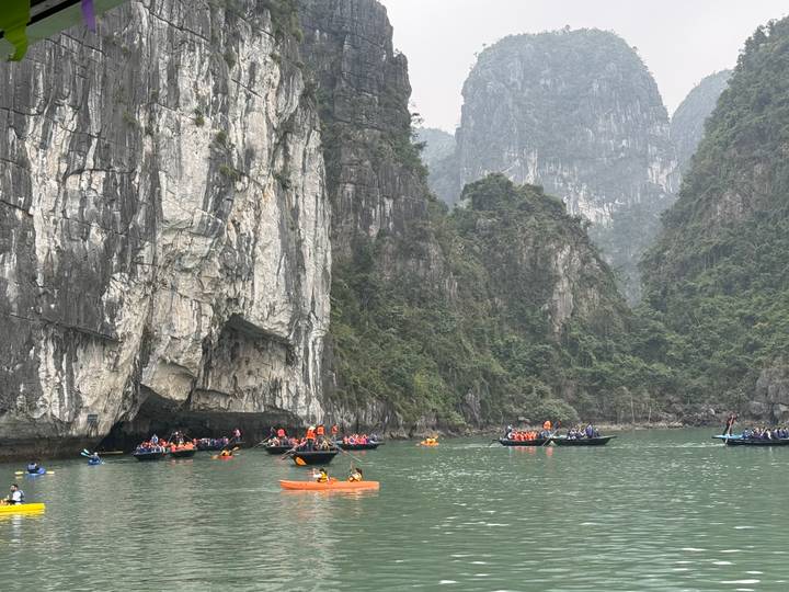 Touristen beim Kajakfahren und Bootfahren in einer Bucht mit Kalkstein-Karst.