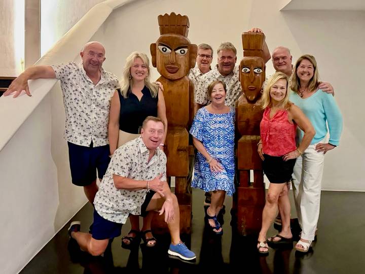 A group of people posing with wooden figures indoors, dressed in casual clothing.