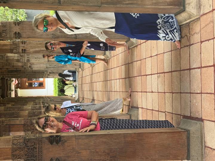 A group of people posing playfully in a temple corridor with intricate wooden carvings.