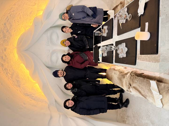 Gruppe drinnen in einem Eisrestaurant mit Eisskulpturen, um einen Tisch sitzend.