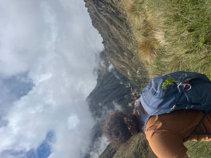Person mit Rucksack blickt auf bewölkte Berge.
