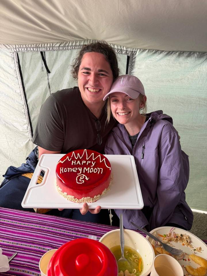 Paar hält einen Kuchen mit der Aufschrift 'Happy Honeymoon'.