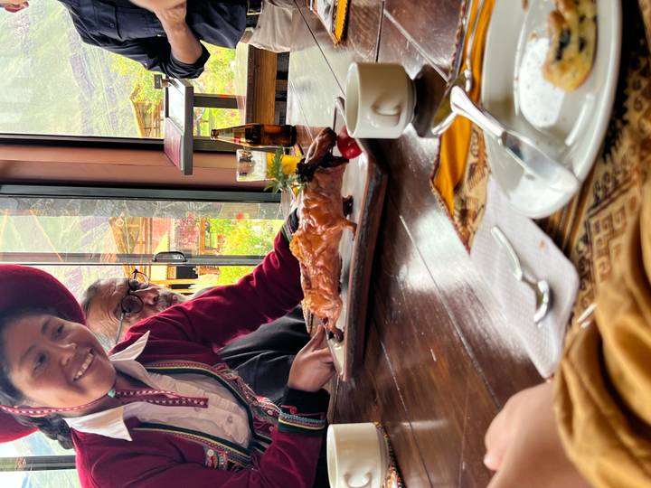 Koch präsentiert ein Gericht den Leuten am Esstisch.