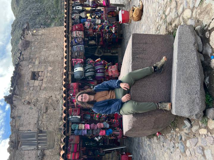 Person, die auf einem Steinblock vor einem Marktstand sitzt.