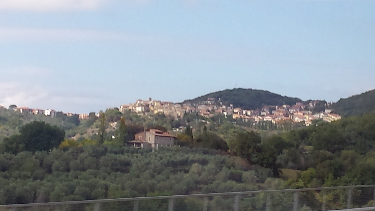 Distant hillside Italian town photographed from a moving vehicle, slightly blurred