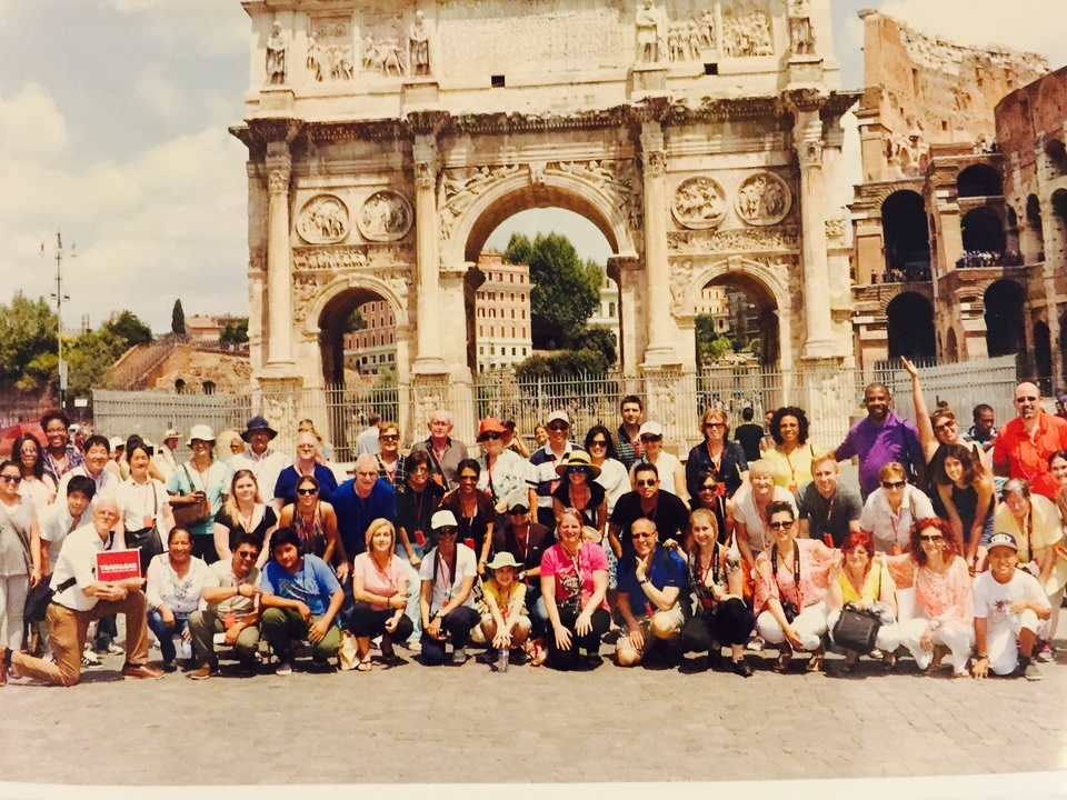 Grand groupe de personnes posant devant une arche historique.