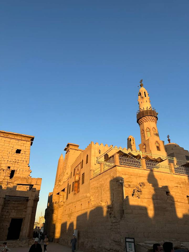 Golden-lit mosque with a tall minaret set against a clear blue evening sky