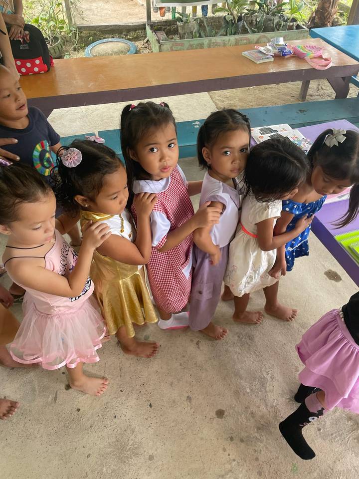 Line of young children in colorful outfits waiting inside a classroom in the Philippines.