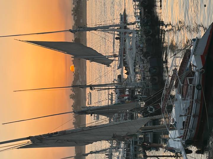 Traditional feluccas moored on the Nile as the sun sets in a vivid orange sky over Aswan