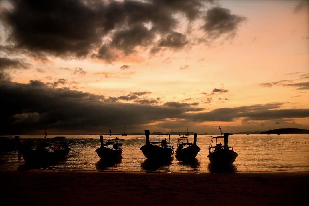 Silhouettes de bateaux lors d'un coucher de soleil spectaculaire.