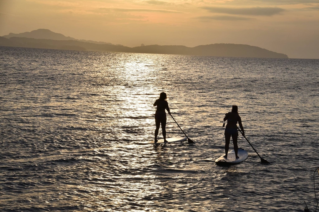 Deux personnes font du paddleboard au coucher du soleil.