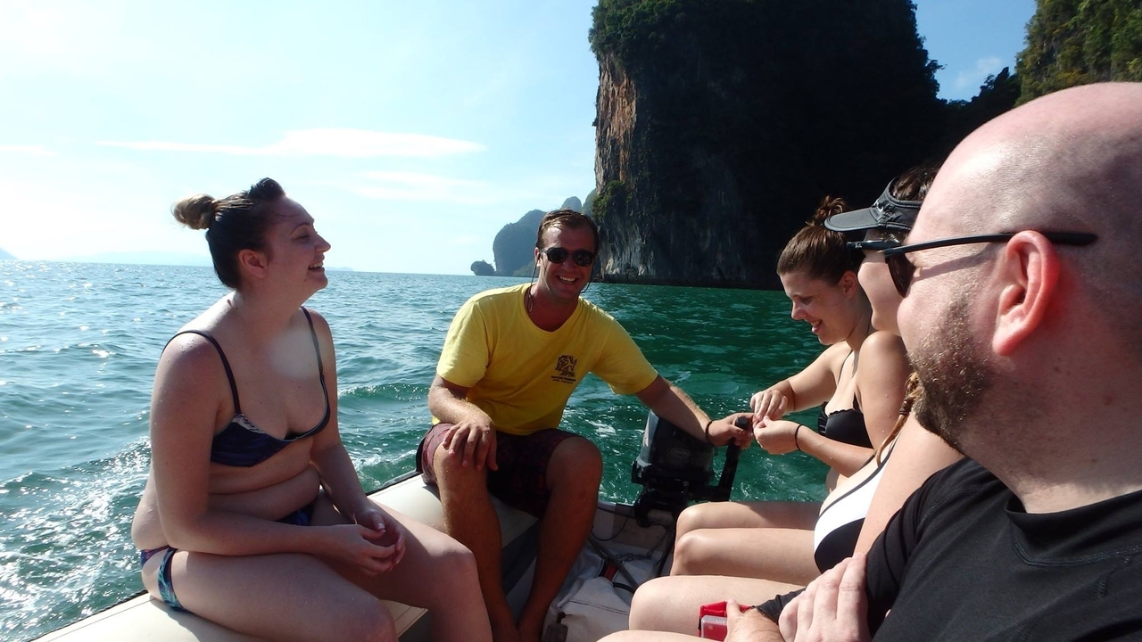 Un groupe d'amis sur un petit bateau à moteur avec une vue panoramique sur la mer et les falaises.