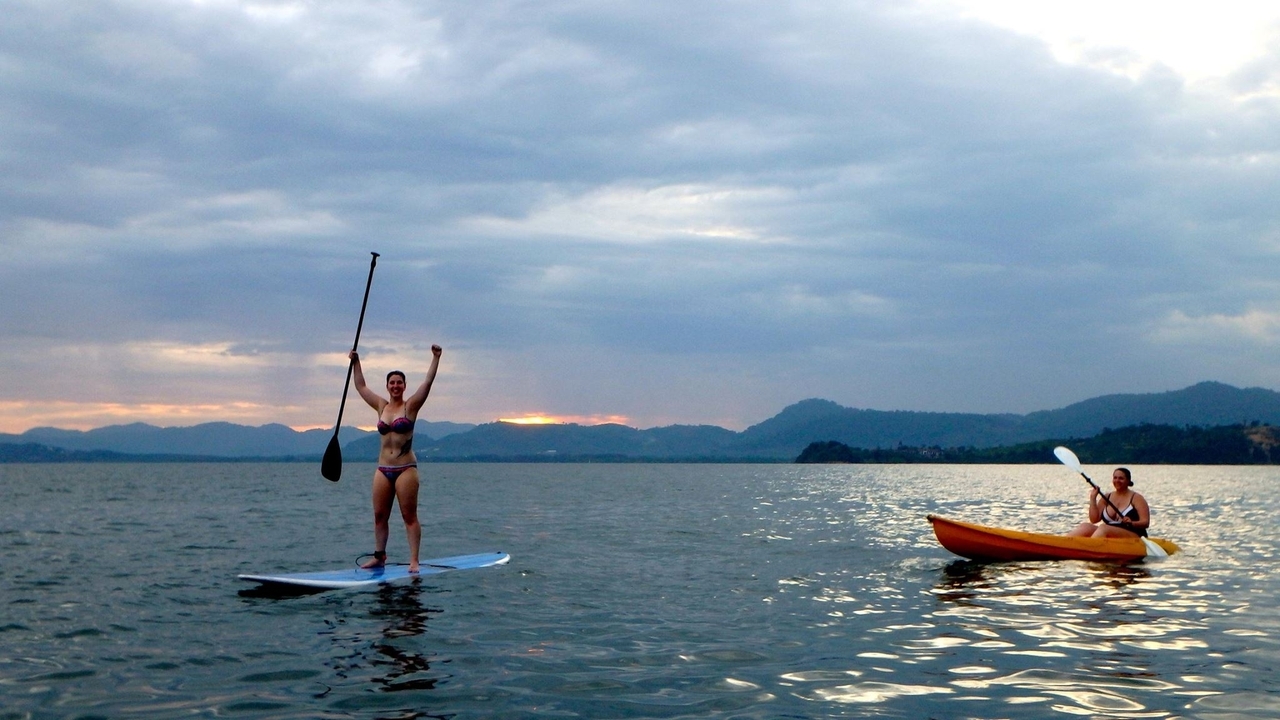 Deux personnes sur un paddleboard et un kayak dans la mer au coucher du soleil.
