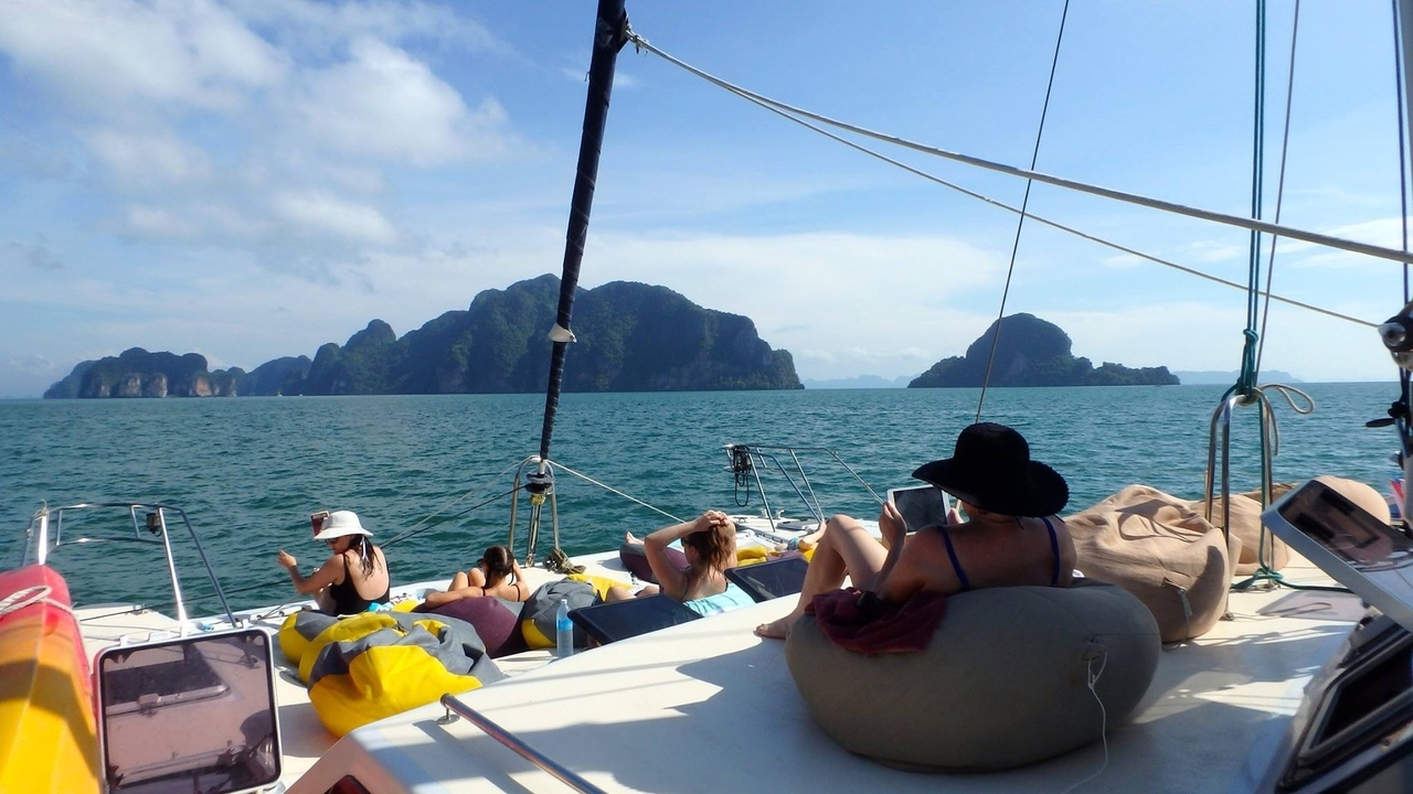 Personnes se relaxant sur un yacht avec vue sur l'océan et les îles calcaires lointaines.